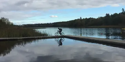 Cyclist on wooden walkway surrounded by water
